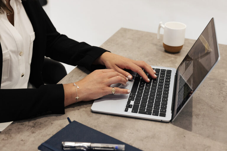 Professional workspace image showing Anna Elliot typing on a laptop during a strategic positioning and commercial growth planning session, used to illustrate AI visibility, structural positioning and competitive differentiation.